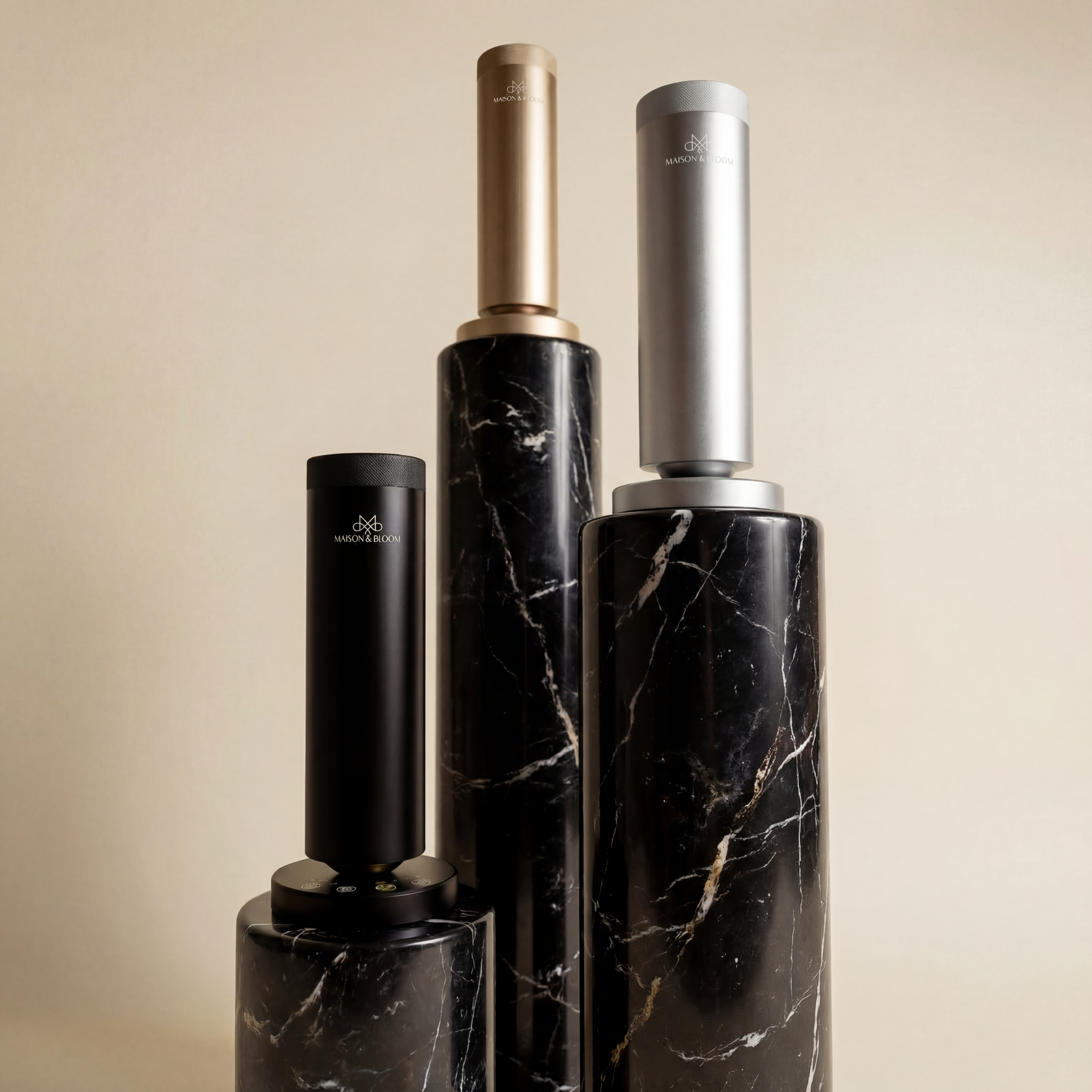 Three modern diffusers in gold, silver, and black on black marble pillars
