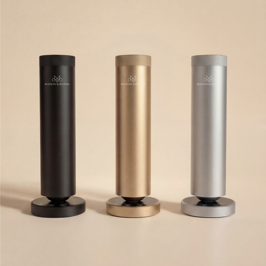 Three modern cylindrical aroma diffusers in black, gold, and silver, standing side by side.