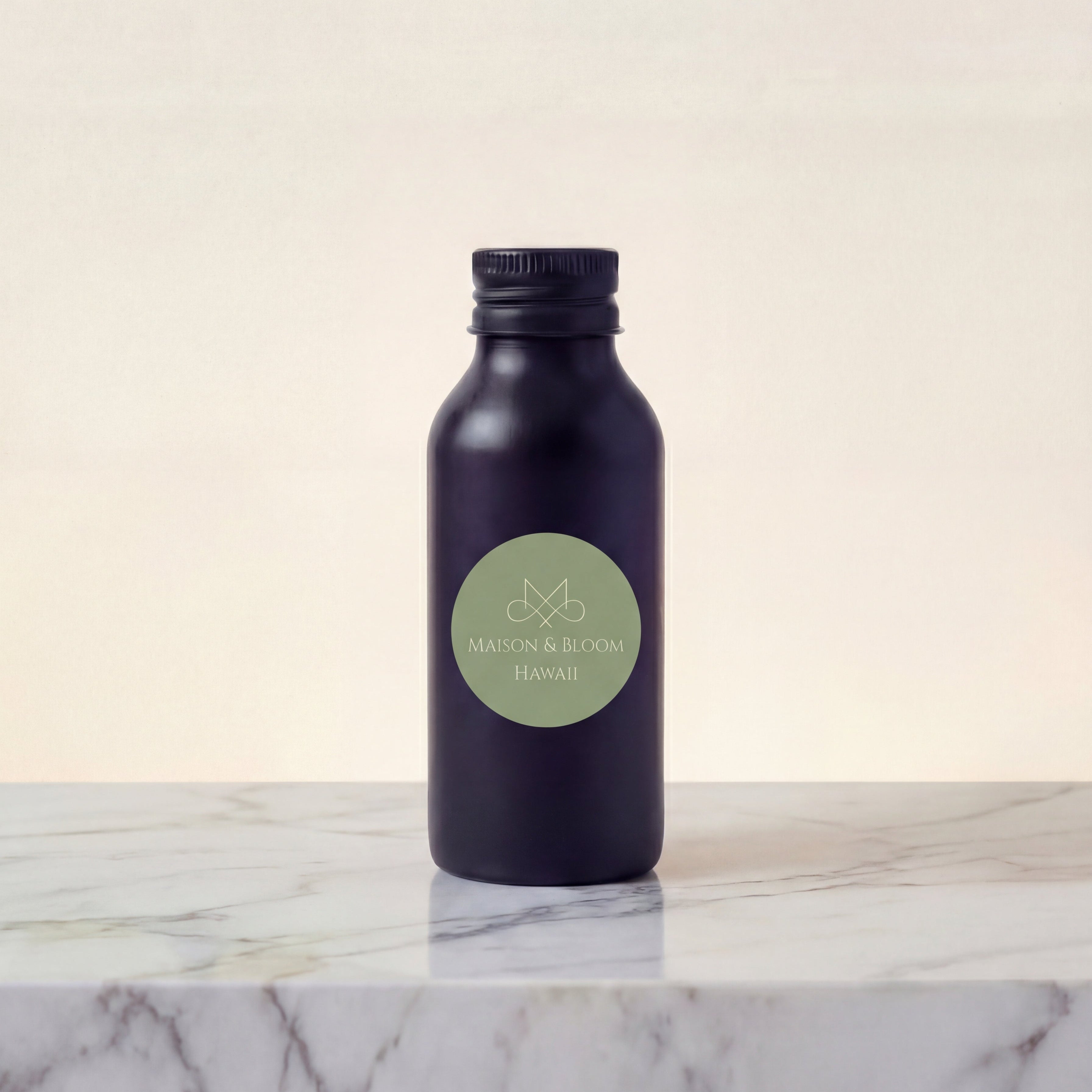 Dark minimalist bottle labeled 'Maison & Bloom Hawaii' on marble surface, neutral background