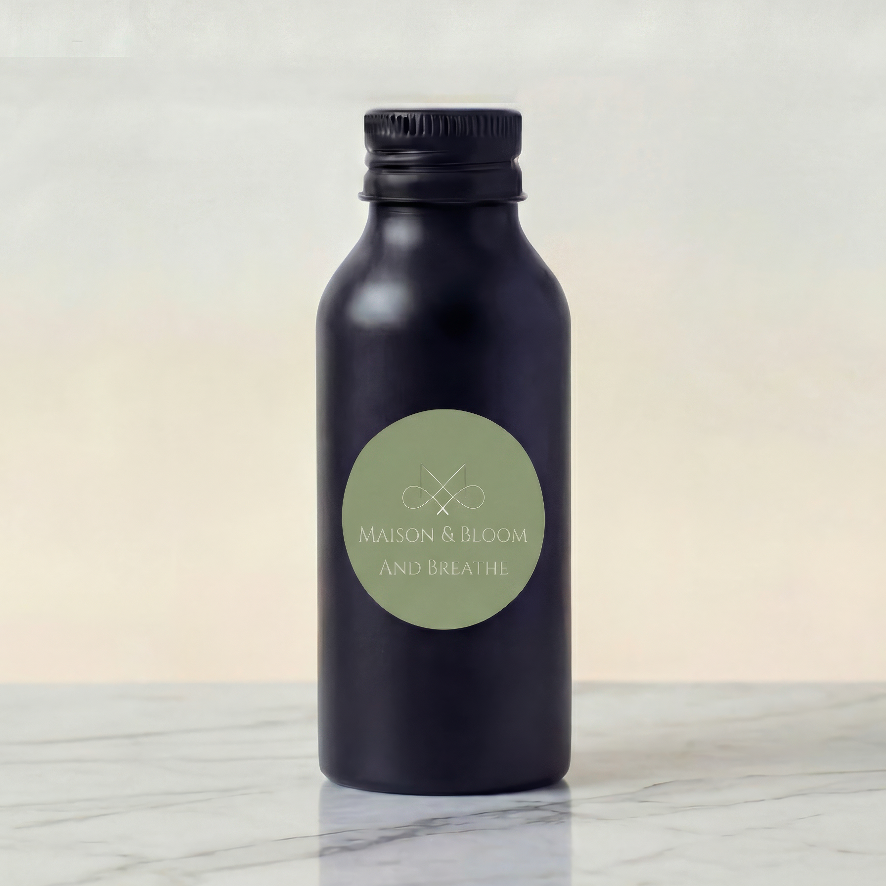 Black bottle labeled 'And Breathe' with sage green label on marble surface