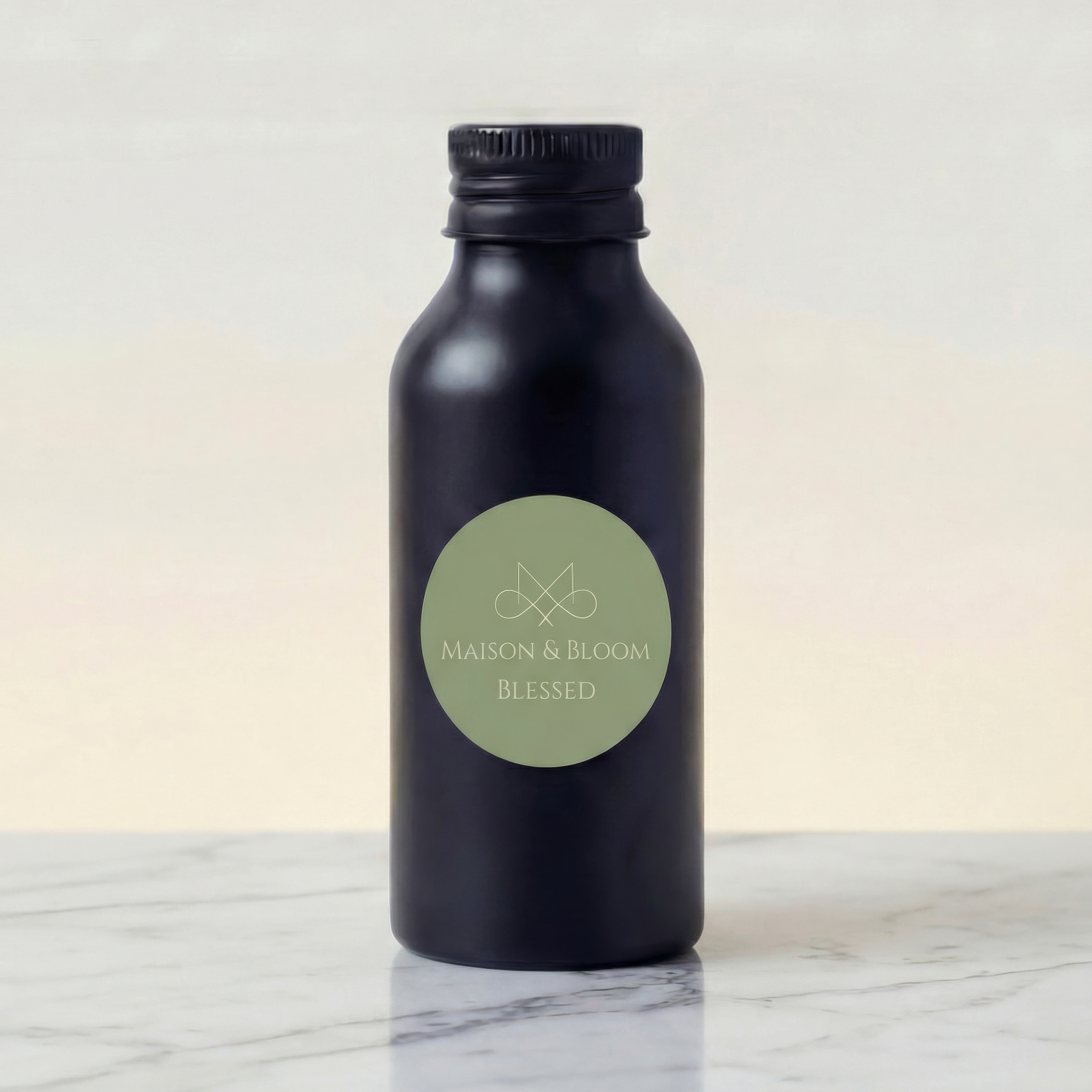 Matte black bottle labeled 'Maison & Bloom Blessed' on marble surface, neutral background
