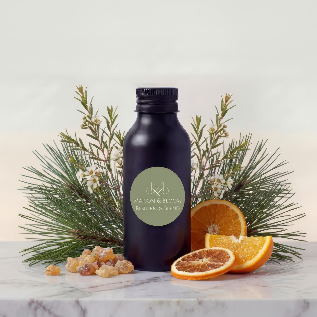 Resilience Blend bottle with pine, orange slices, and frankincense on marble surface