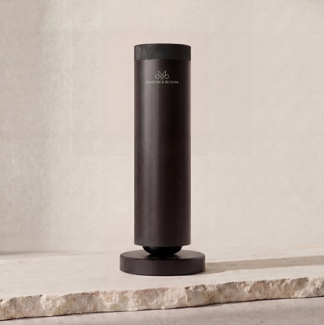 sleek black cylindrical diffuser with logo on light stone surface, minimalist aromatherapy decor